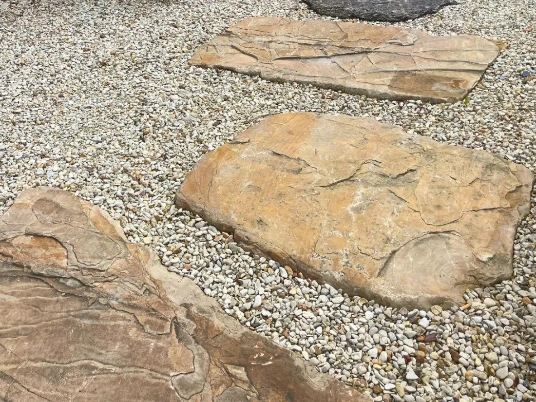 Pas japonais Aragone en pierre beige posés dans un lit de gravier clair