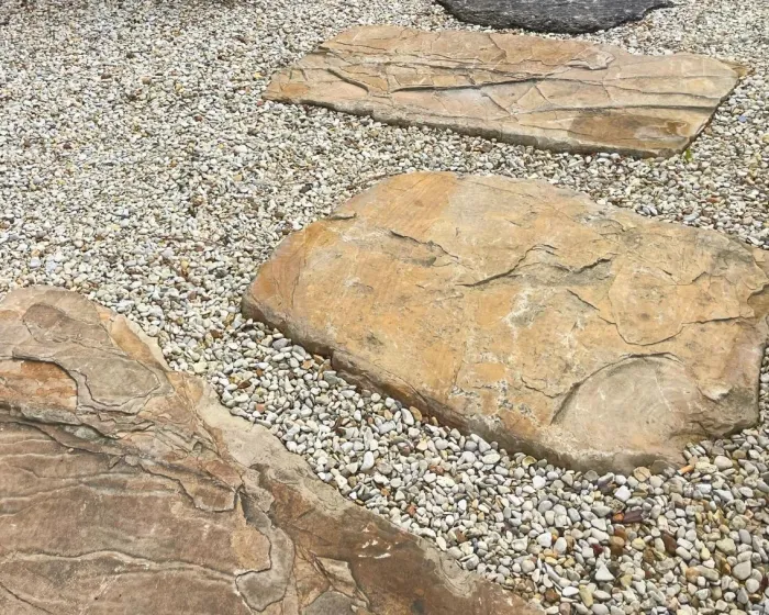 Pas japonais Aragone en pierre beige posés dans un lit de gravier clair